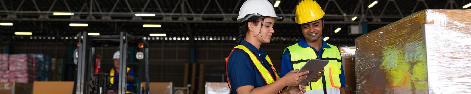 Photo: Technical workers review training lessons on a tablet device in a warehouse.